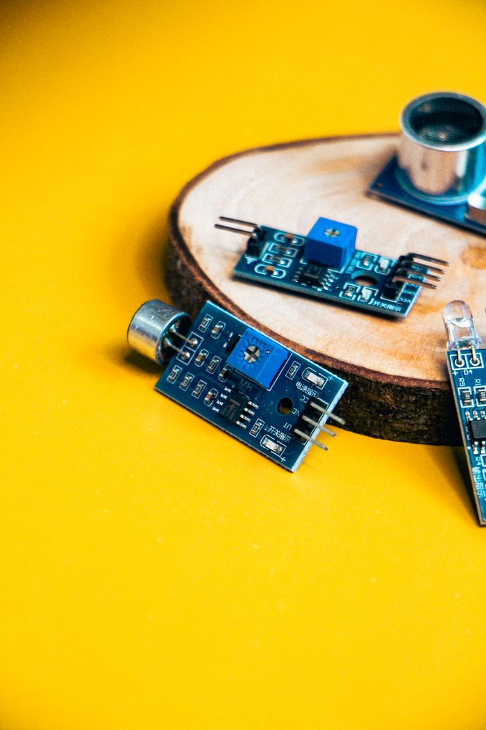 Close-up of robotics components on a vibrant yellow background with wooden base.